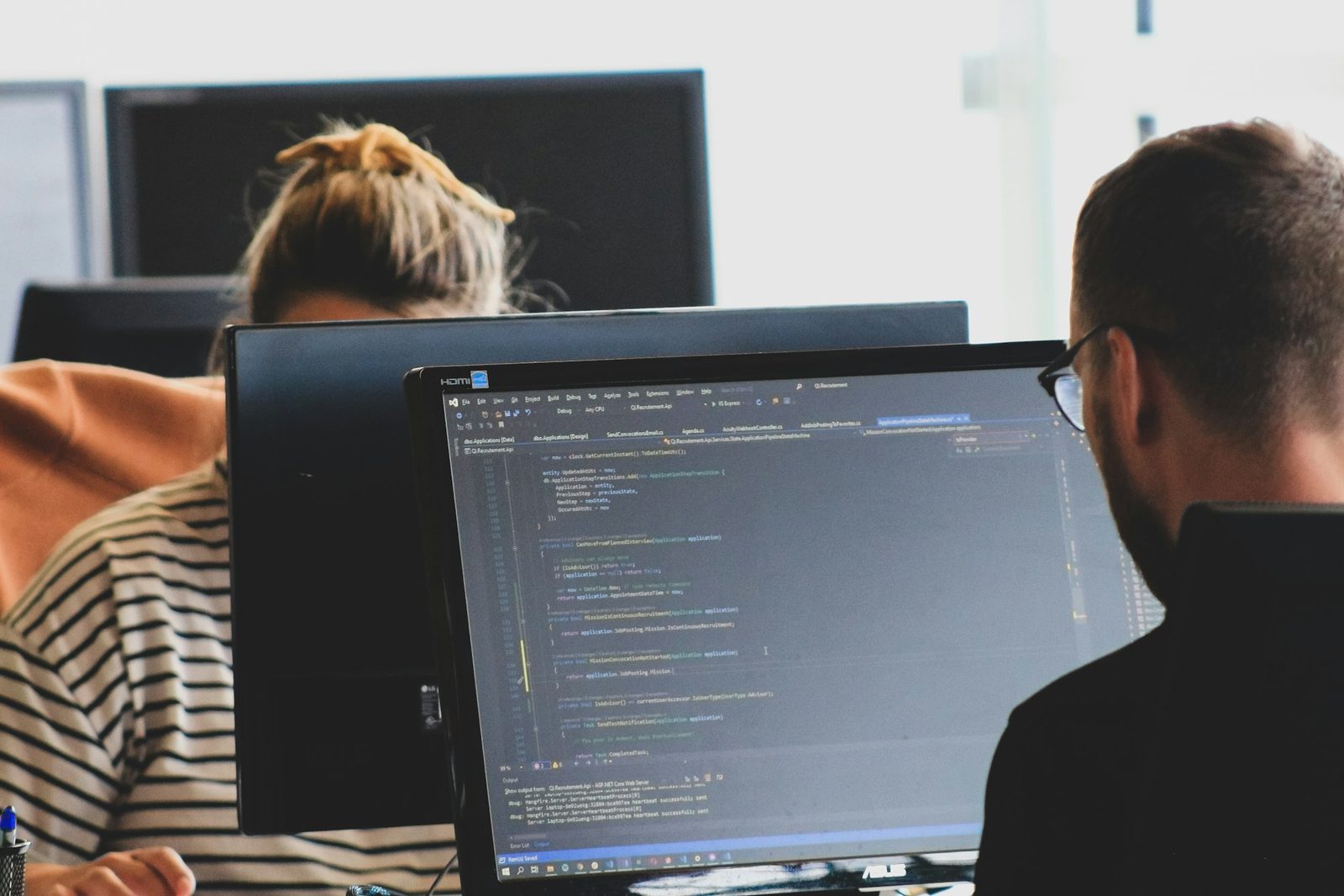 Deux développeurs devant des écrans de code dans un bureau de PME