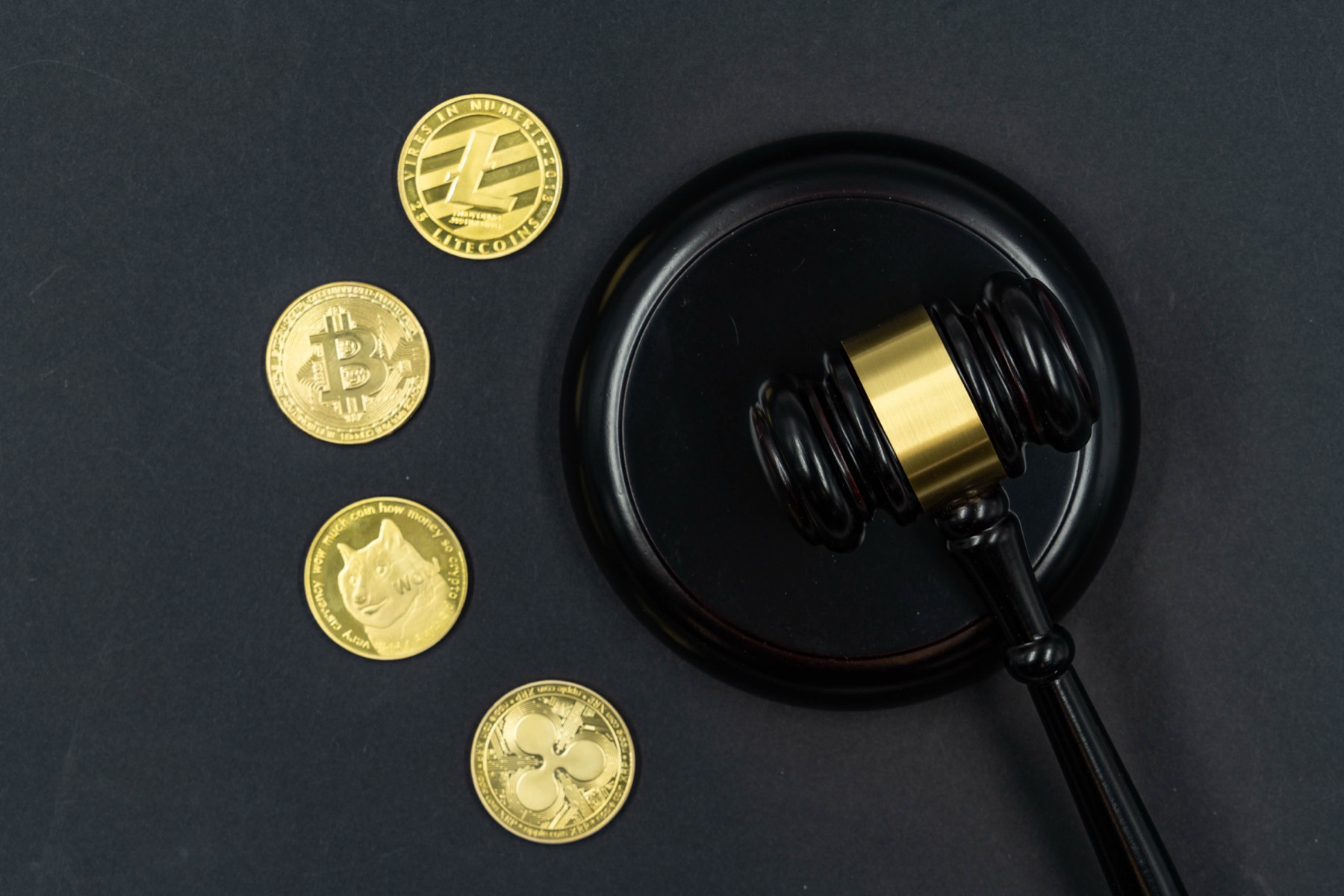 marteau de juge posé à côté de pièces de cryptomonnaie dorées sur fond sombre, symbolisant la réglementation des crypto-actifs