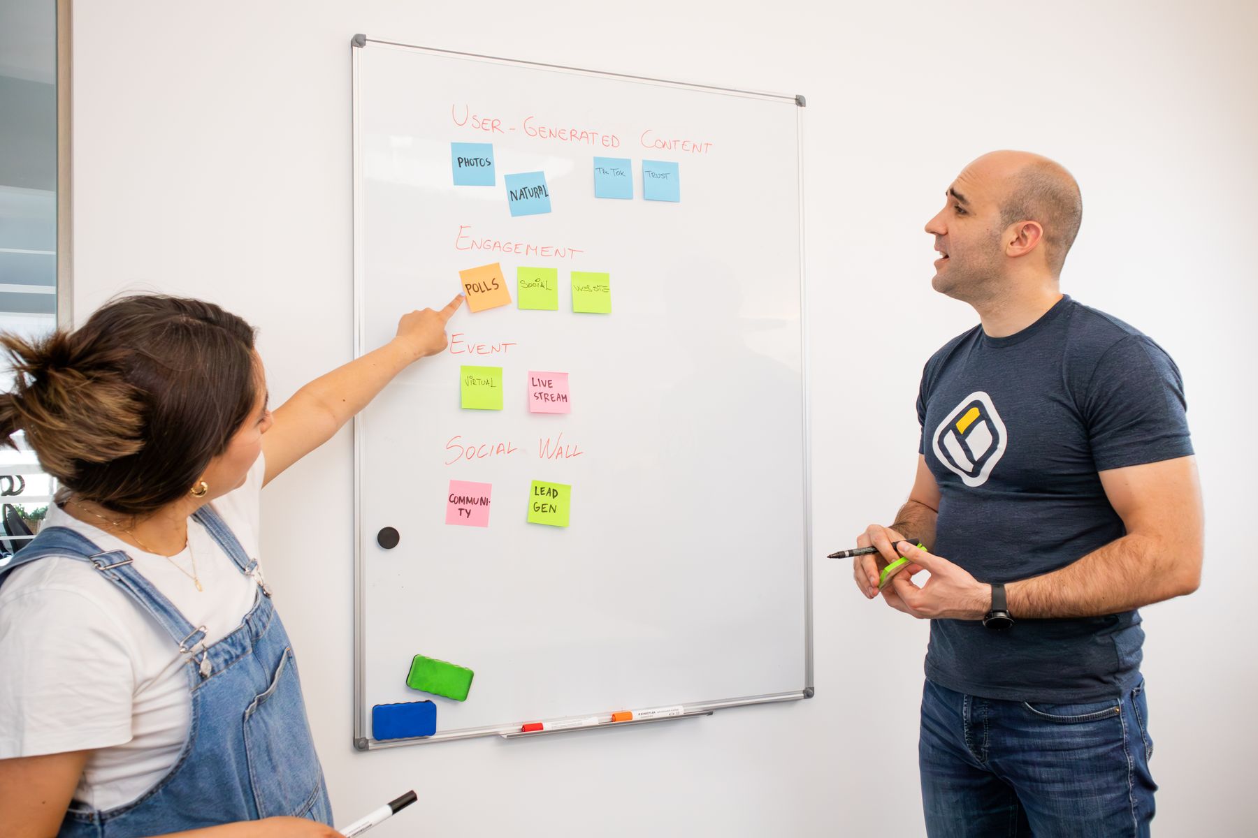 Deux collègues organisent des post-it de couleur sur un tableau blanc pendant un atelier de travail