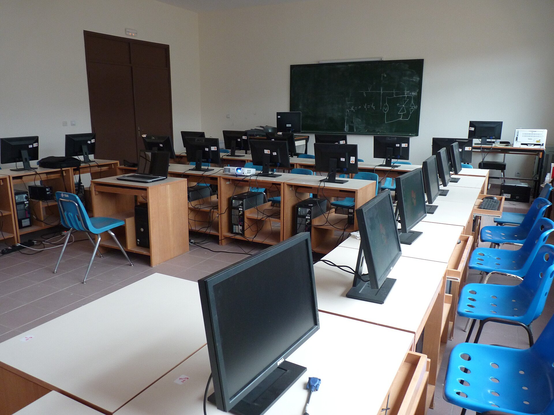 Salle informatique de l'École normale supérieure d'Abidjan, rangées d'ordinateurs sur des tables blanches et chaises bleues